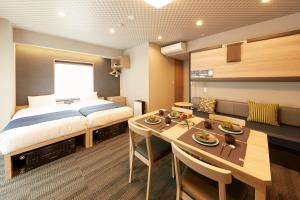 东京MONday Apart Premium UENO OKACHIMACHI的一间卧室配有一张床铺和一张桌子,还有一间用餐室