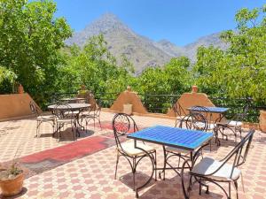 伊姆利尔Riad Atlas Garden的庭院配有桌椅,背景为山脉