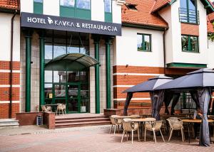 Czersk PomorskiHotel KAVKA & Restauracja的大楼前的餐厅,配有桌子和遮阳伞