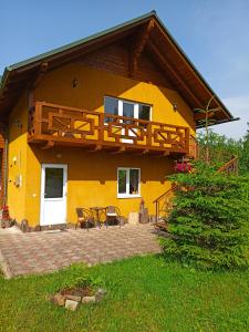 斯拉夫西克Приватна Садиба Потічок的黄色的房子设有阳台和庭院