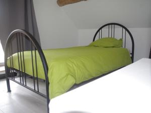 Saint-Sernin-du-Plain勃艮第谷仓度假屋的一张带绿色床单和枕头的黑色金属床