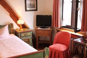 罗滕堡施皮茨韦格酒店的一间卧室配有一张床、一把椅子和电视