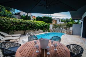 圣拉斐尔Villa de Charme La Lionne-Piscine-12 pers的一张带椅子的木桌和一把遮阳伞,毗邻游泳池