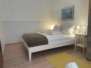 伍珀塔尔Gehen & Fahrrad Elberfeld的卧室配有白色床、台灯和桌子