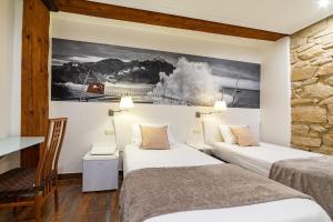 圣塞瓦斯蒂安阿依达旅馆的酒店客房设有两张床,墙上挂有绘画作品