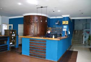 大普拉亚Ibericas Praia Hotel的坐在酒吧里,在一间有蓝色墙壁的房间里坐着的女人