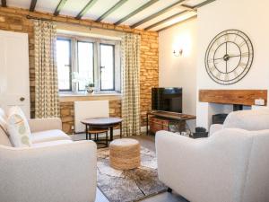 切尔滕纳姆Well Cottage的客厅配有白色家具和墙上的时钟