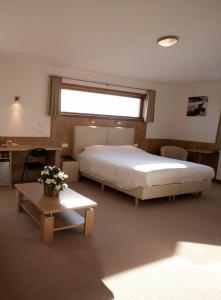 鲁瑟拉勒璨多尔酒店的一间卧室配有一张大床和一张鲜花桌