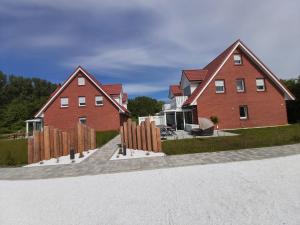 吕根岛上的维克Sonneninsel & Ankerplatz Wiek的两栋红砖房屋,设有木栅栏