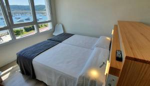 穆希亚Apartamentos Costa da Morte Muxia的一间卧室配有一张带梳妆台和窗户的床。
