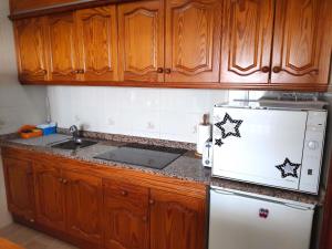 蒂亚斯El timple的厨房配有木制橱柜和白色冰箱。