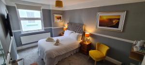 兰迪德诺Sunnycroft Private Hotel的一间小卧室,配有一张床和一张黄色椅子