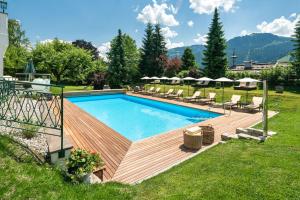 基茨比厄尔Tennerhof Luxury Chalets的庭院旁的一个带木甲板的游泳池