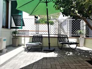 里奥马哲雷Amore Cove Apartment - Riomaggiore - 5 terre的庭院里设有两把椅子和一把绿伞