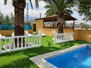 卡索拉CASA LOS ANGULOS的后院拥有白色的围栏和棕榈树,设有游泳池
