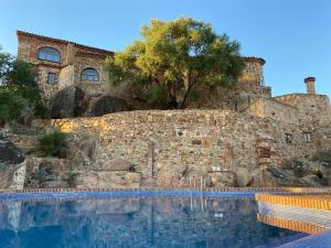 AlmendralHotel Monasterio de Rocamador的一座石头建筑前的大型游泳池