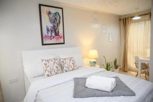 内罗毕Furnished 1 Bedroom Apartment in Nairobi. 15 Mins to CBD. Free WI-FI & Parking的卧室配有白色的床和毛巾