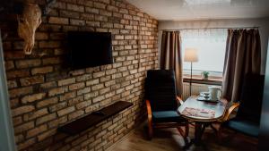 比亚瓦波德拉斯卡Browar Osjann - pokoje gościnne的一间设有砖墙、桌子和电视的客房