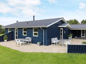 伦斯楚普Holiday home Hjørring IV的蓝色的房子,前面设有椅子和桌子