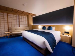 京都Homm Stay Nagi Shijo Kyoto By Banyan Group的酒店客房带一张大床和一把椅子