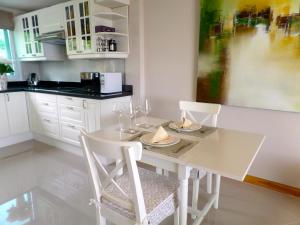 南芭堤雅韦斯特伯里公寓酒店的白色的厨房配有白色的桌子和椅子
