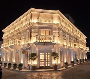 都拉斯Giulia Albérgo Hotel的白色的建筑,晚上有灯光的外墙