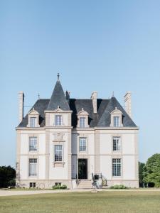贝诺代Les Garennes - Hôtel Spa Bénodet的黑色屋顶的大型白色房屋