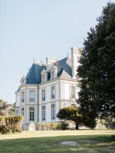 贝诺代Les Garennes - Hôtel Spa Bénodet的前面有一棵树的大白色房子