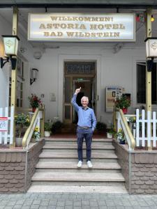 特拉本特拉巴赫Astoria Hotel Bad Wildstein的站在酒店前面台阶上的男人
