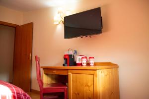 卡迈格拉特罗希拉诺Abete Bianco - Albergo del Natale的客房设有一张木桌,墙上配有电视。