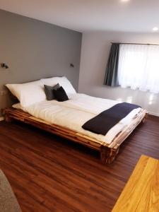 NesslauGasthaus Gemsli的一间卧室设有一张大床,铺有木地板