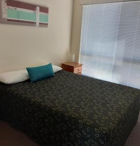 埃默拉尔德翡翠公寓式酒店的一间卧室配有一张带蓝色枕头的床