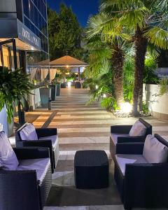加尔达湖滨拉佩而拉酒店的一座建筑前方的庭院,庭院内配有沙发和棕榈树