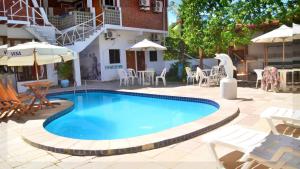 嘎林海斯港Che Lagarto Hostel Porto de Galinhas的庭院内的游泳池,配有桌椅
