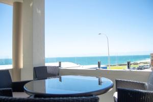 珀斯Cottesloe Beach View Apartments #7的一张带椅子的玻璃桌,享有海景
