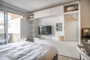 阿卡雄La Pomponnette du Bassin的一间白色卧室,配有床和电视