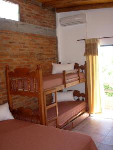 Gualeguaychú拉卡索纳酒店的带两张双层床和砖墙的客房