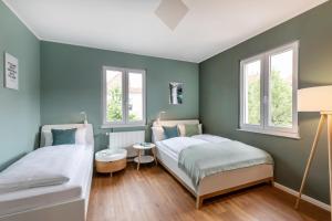 辛根PRIMERA Villa的配有两张床铺的绿色墙壁和窗户