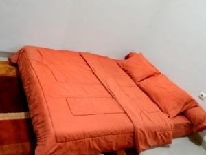 伦邦Villa Lembang Syariah near park & Zoo的床上的橙色毯子
