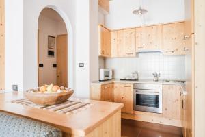 博萨迪法萨多洛米亚住宅公寓式酒店的厨房配有木制橱柜和柜台上的一碗水果