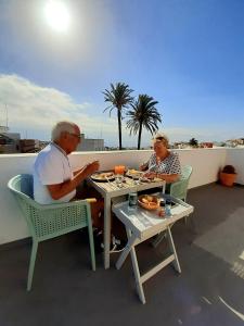 因赫尼奥Villa Nestor的两个人坐在桌子旁,在阳台上吃食物