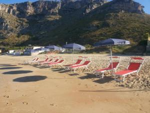 斯佩隆加DEPANDANCE SUL MARE的海滩上的一排椅子和遮阳伞