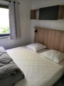 比斯卡罗斯Mobil Home camping 5 étoiles Biscarrosse的卧室内的一张带两个枕头的床