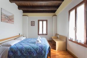 普雷甘齐奥尔Alla Barchessa di Villa Querini的一间卧室配有一张蓝色棉被和两个窗户。