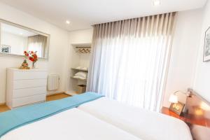 波瓦-迪瓦尔津Apartamento Mar & Sol的卧室配有白色的床和窗户。