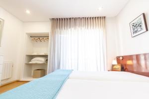 波瓦-迪瓦尔津Apartamento Mar & Sol的卧室设有一张白色大床和一扇窗户。