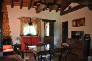TenzuelaCasa Rural Los Regajales的客厅配有桌子和红色沙发