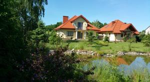 卡齐米日-多尔尼Apartamenty Zaczarowany Ogród的池塘旁有红色屋顶的房子