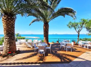 卡普多兰多Villa Anita Apartments的一间种有棕榈树和桌子的餐厅,享有海景