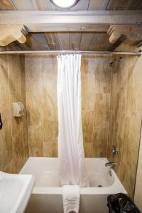 ChamaChama Trails Motel的带浴缸和白色淋浴帘的浴室